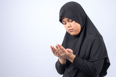 Girl in hijab praying over white background