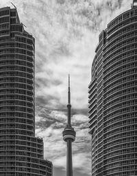 Low angle view of buildings in city against cloudy sky