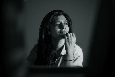 Close-up of woman looking away sitting in darkroom