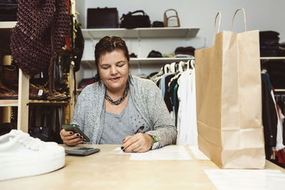 Businesswoman calculating on table at clothing store