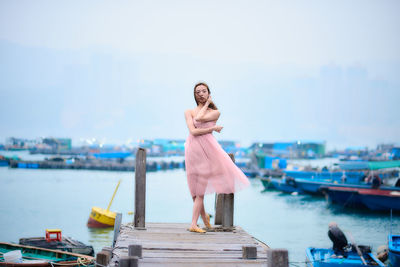 Woman standing on pier over sea against sky