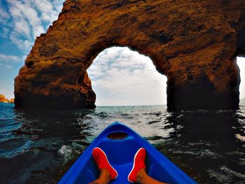 Low section of person traveling in boat against natural arch