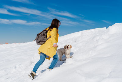 Woman with dog on snowcapped mountain against sky