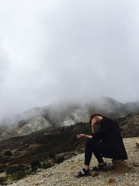 Rear view of woman standing on mountain against sky