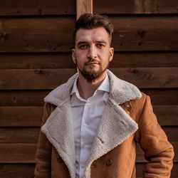 Portrait of young man standing against wall