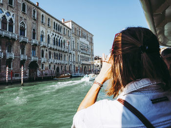 Rear view of woman with umbrella in canal