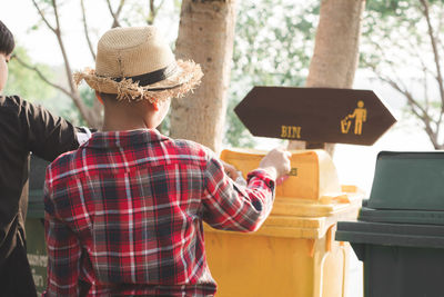 Rear view of boy putting garbage in can