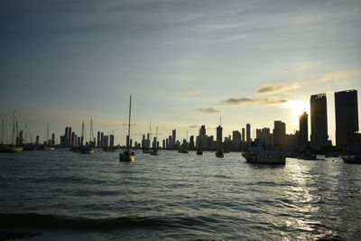 Sea and cityscape against sky during sunset