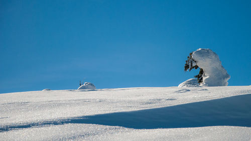 People on snowcapped mountain against clear blue sky