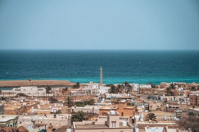 High angle view of townscape by sea against clear sky