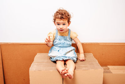 Portrait of smiling girl sitting against wall at home