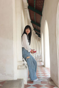 Full length of woman sitting on floor in corridor