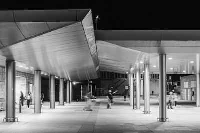 People walking in corridor of building at night