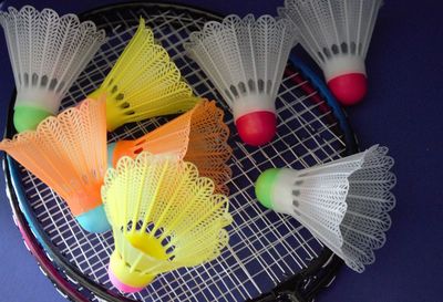 High angle view of multi colored shuttlecocks and rackets on table