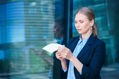 Business woman in suit is in city center against backdrop building, writes