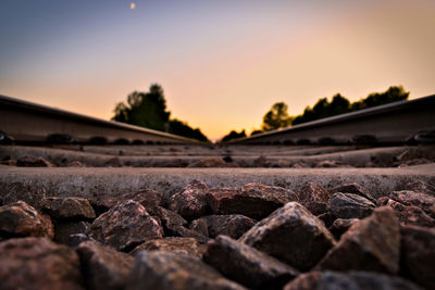 Surface level of stones on railroad track against sky during sunset