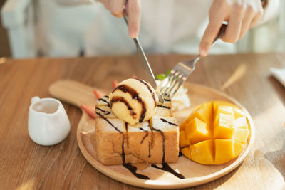 Close-up of hand holding ice cream on table