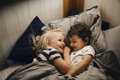 Smiling siblings sleeping in bedroom at night