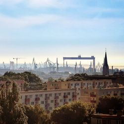 Buildings and cranes against sky in city