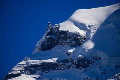 Snow covered mountain against clear blue sky