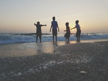 People on beach against clear sky during sunset