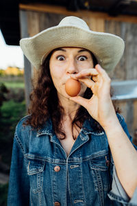 Funny woman farmer in denim with a fresh egg, making a funny face