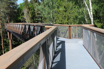 Empty footbridge against trees