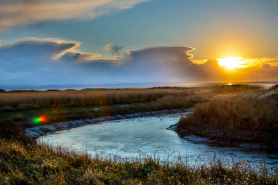 Frozen lake along countryside landscape at sunset