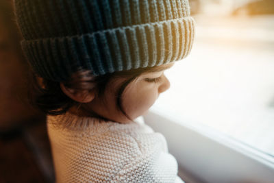 Close-up of cute boy sitting by window