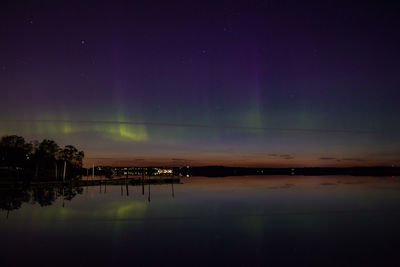 Scenic view of aurora borealis over calm lake against sky at night