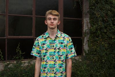 Portrait of young man standing against window