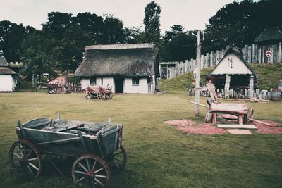 Chairs and table on field by house against sky