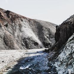 Water flowing through rocks against clear sky