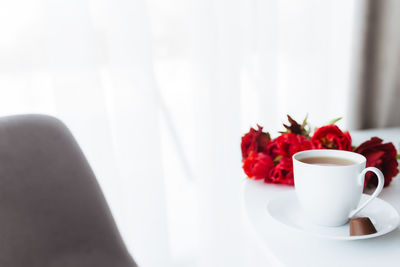 Close-up of coffee and red rose on table