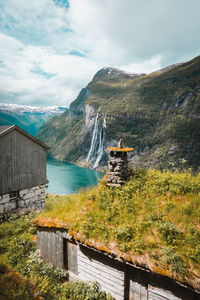 Scenic view of farm, waterfall, fjord and mountains against sky