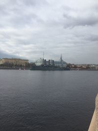 City at waterfront against cloudy sky