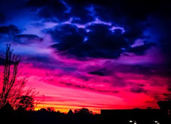 Low angle view of silhouette trees against dramatic sky