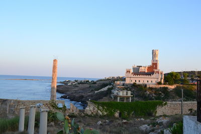 Buildings by sea against clear sky