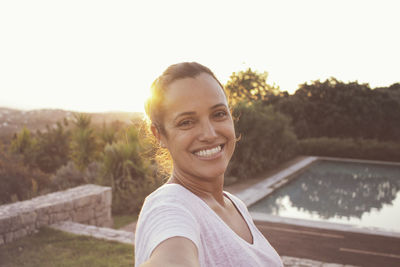 Portrait of smiling young woman against swimming pool