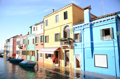 Boats moored in canal by buildings against sky in city