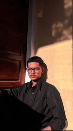 Portrait of young man standing against wall