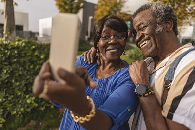 Happy senior couple taking selfie through smart phone at park