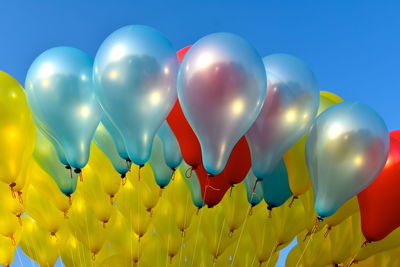 Low angle view of balloons against blue sky