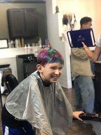 Smiling boy with dyed hair standing in barber shop