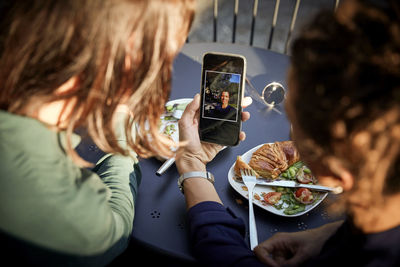 Midsection of woman using mobile phone while sitting on table