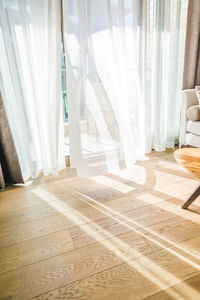 Modern room interior with an open window in minimal style. transparent tulle with morning sun rays 