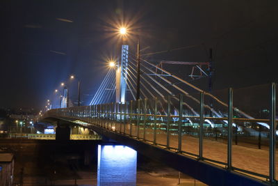 Illuminated bridge over river in city at night