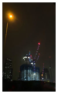 Low angle view of illuminated buildings against sky at night