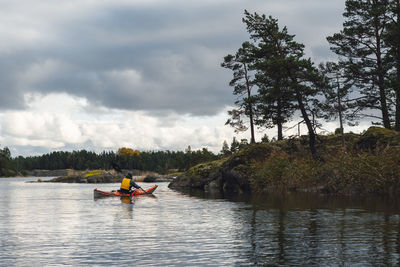 People kayaking in sea against sky