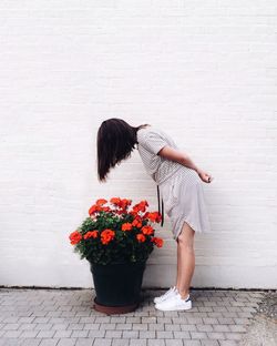 Woman standing by flowers against wall